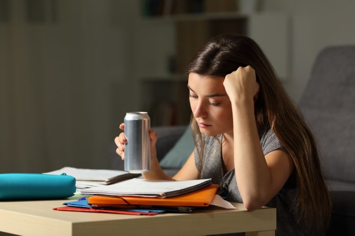 Student memorizing holding and energy drink in the night
