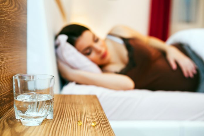 Pregnant woman resting with pills at hand
