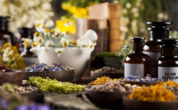 Alternative medicine, dried herbs and mortar on wooden desk background