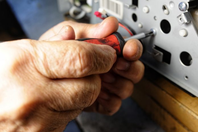 technician repairs photocopier with screwdriver