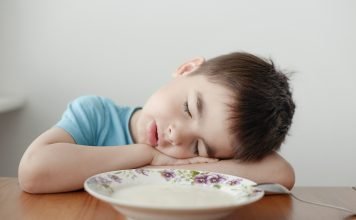 A tired boy sleeping over his porridge