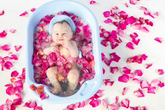 baby girl bathing in a bathtube with rose petals in studio