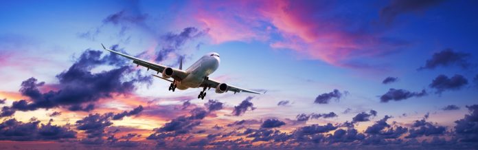 Jet plane is maneuvering for landing in a spectacular sunset sky. Panoramic composition.
