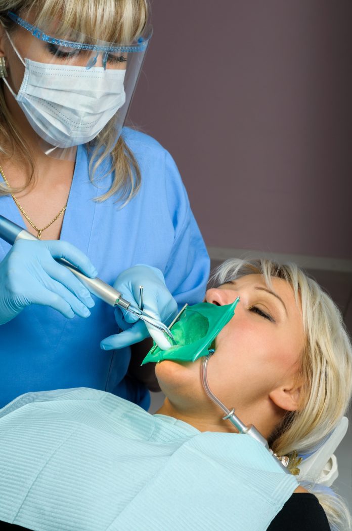 dentist with patient, using dental curing light