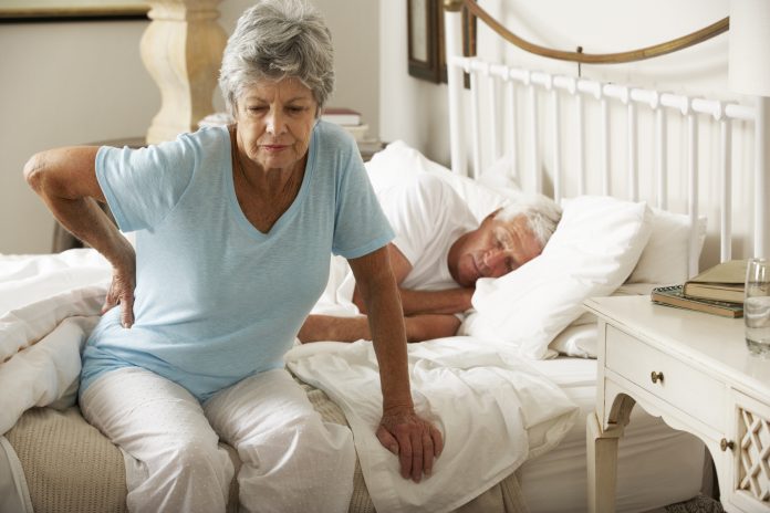 Senior Woman Suffering From Backache Getting Out Of Bed