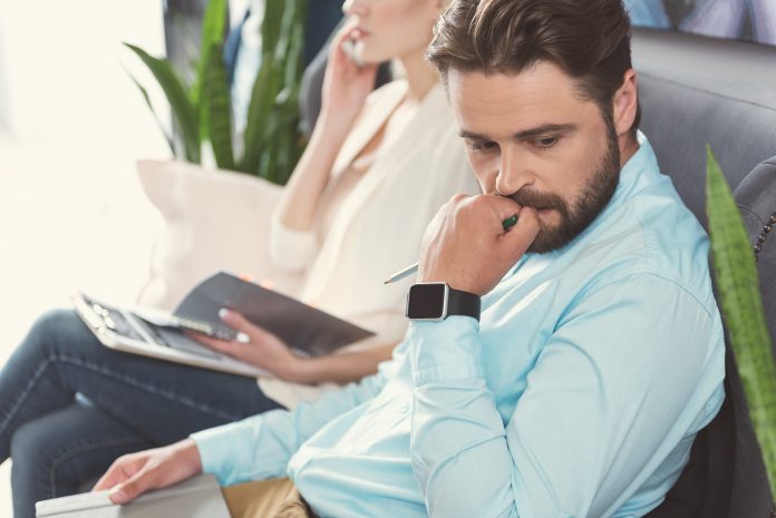 Nervous bearded guy waiting in queue for job talk indoor