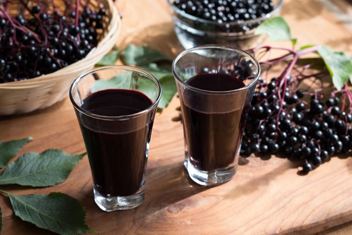 Two glasses of elderberry syrup on a wooden table