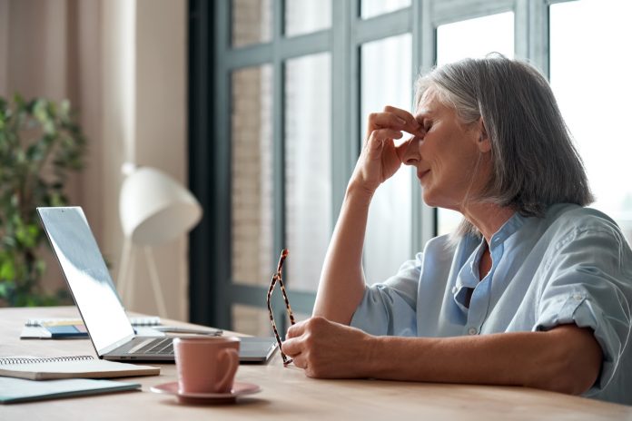 Tired old business woman takes off glasses feeling eye strain from computer.