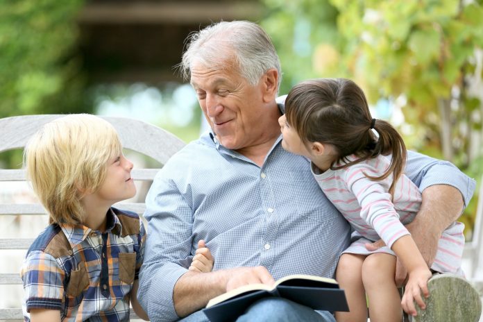 Senior man reading book with grandkids