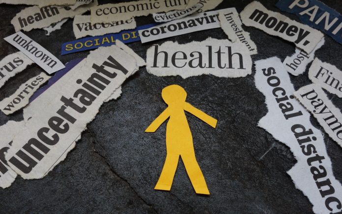 Paper man surrounded by Corona Virus and economic news headlines