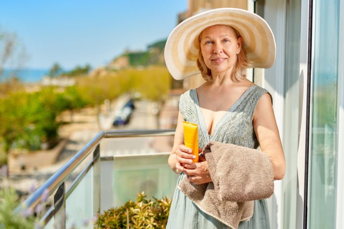 Happy mature woman on balcony at home with sea shore.