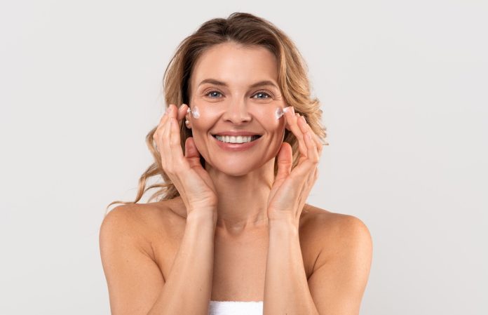 Antiage Treatment. Beautiful Caucasian Woman Applying Moisturizing Cream On Face