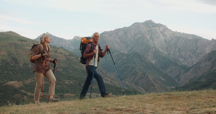 Active senior caucasian couple hiking in mountains with backpacks, enjoying their adventure 4k