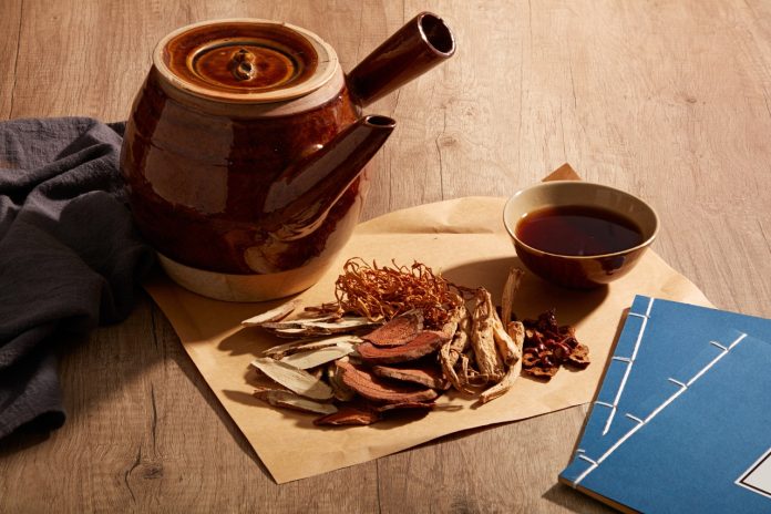 Herbal tea with herbs and books on the wooden table