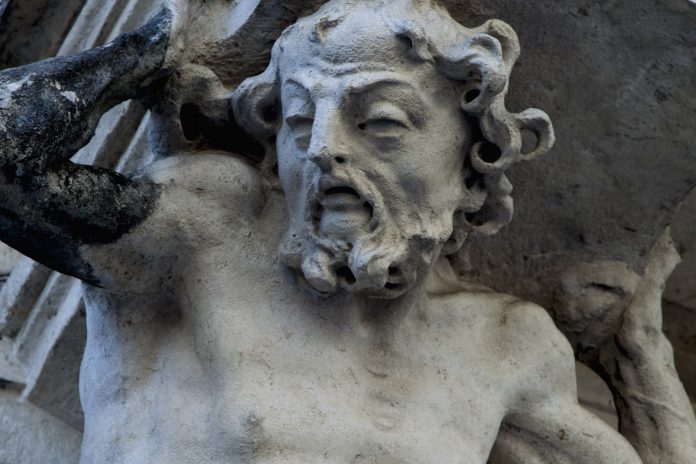 Ancient statue of Sisyphus with stone. God Zeus punished Sisyphus: he had to roll very big stone to top of high mountain rock, which beforу reach the top rolled back down every time.